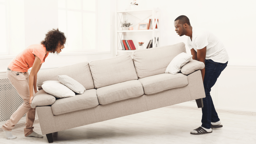 Couple moving oversized couch to depict how to move oversized items